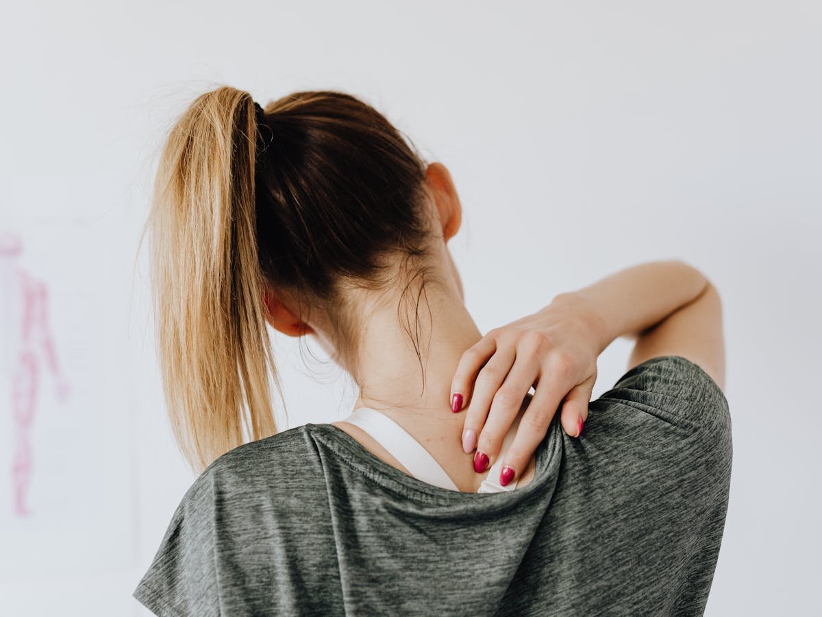 A person holding her neck and shoulder in pain — common presentation after a motor vehicle accident or whiplash injury